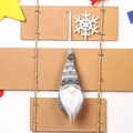 Close-up of a knitted Christmas gnome ornament with white beard on a rustic wooden background - Gray Type C
