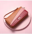 Detail view of tri-color patchwork leather wallet with double zippers and wrist strap - Camel