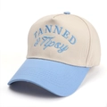 Dettaglio del ricamo blu TANNED & Tipsy su cappello da baseball beige a cinque pannelli - Beige con Blu Chiaro