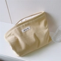 Close-up of cream corduroy cosmetic bag with vertical texture and simple wish label - Light Yellow