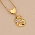 Detailed shot of golden letter G pendant with colorful cubic zirconia and heart link - Letter G / Gold