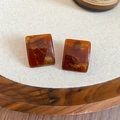 Detail of amber resin square stud earrings with gold leaf textures on a soft white fabric - 70# Silver Earring Post-Brown-Square Gold Foil Amber
