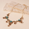Dettaglio della collana floreale con cristalli blu e pendenti color ambra su pietra - Oro