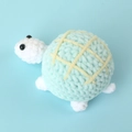 Handmade crochet turtle plush in white and light blue with soft yellow grid shell patterns - Cake Costume Little Turtle