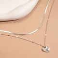 Detail van een zilveren dubbellaagse ketting met hartjeshanger en een slangenbotketting - Dubbele Laag Hart Slangenketting / Zilver