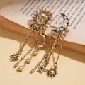 Pendientes retro dorados con sol, luna, estrellas y perlas sobre fondo de libro antiguo - Dorado