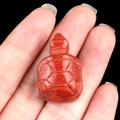 Miniature red jasper stone turtle carving held in hand to demonstrate its small size - Red Jasper