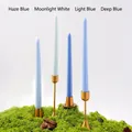 Juego de cuatro velas cónicas azules en soportes dorados sobre musgo verde natural - Serie Azul