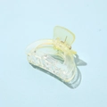 Detailed view of a transparent light yellow acetate hair claw clip on light blue surface - Semi-circular Yellow