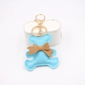 Detailed close-up of sky blue PU leather bear keychain with brown bow on white box - Light Blue