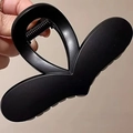 Elegant matte black heart-shaped hair claw clip with bow design in a hand-held view - Matte Black