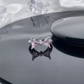 Macro shot of silver bow ring with pink zircon crystals on reflective surface - Style 2 Adjustable Ring