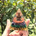 Detailed view of handmade crystal pyramid with golden Buddha and chakra stone layers - Style 20