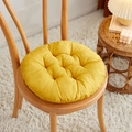 Thick solid yellow round chair cushion on a wooden chair in a cozy home setting - [Round] Ginger Yellow