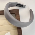 Close-up of a grey sponge headband with soft fabric texture on a wooden display stand - Gray