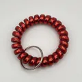 Close-up of a red matte spiral coil wristband keychain with a durable silver metal ring - Metallic Red
