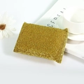 Estropajo dorado para limpieza de cocina junto a una revista sobre un fondo blanco - Dorado