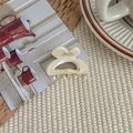 Close-up of a cream-colored heart hair claw clip with Borrette La France text on fabric - Cheese White