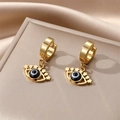 Detailed close-up of golden evil eye huggie earrings with star charms on silk - Black Star Eye