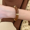 Detalle de pulsera de segmentos de acrílico ámbar con anillos dorados en la muñeca - Estilo 1 - Color Café Oscuro