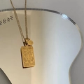 Golden stainless steel Capricorn zodiac necklace with rectangular pendant on reflective surface - Capricorn