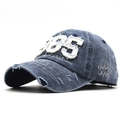 Dettaglio di un cappello baseball in denim vintage blu con ricamo 1985 e strappi - Taglia unica / Blu navy