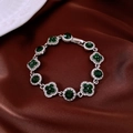 Gros plan détaillé du bracelet vintage argenté avec pierres vertes et strass sur soie - Argent-Vert-Fleur