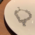 Bracciale a catena argento con ciondolo a orso e perline su un piatto bianco - Argento