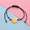 Detail of minimalist black braided wax cord bracelet with a polished gold circular charm - Gold