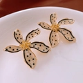 Detail von cremefarbenen Blumenohrringen mit schwarzen Punkten und goldenem Kern auf Teller - Gold (Silberner Ohrringstecker)