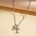 Détail de doubles pendentifs croix argentés avec strass brillants sur une chaîne en métal - Argenté