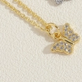 Close-up of golden butterfly pendant with micro-pave cubic zirconia on a delicate chain - Full Zircon Butterfly / 14K Gold