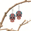 Detail of vibrant orange sugar skull earrings with floral relief on rustic wooden branches - Orange Blue Purple Day of the Dead Style