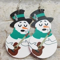 Detail of leather snowman earrings with guitar and festive scarf on stone background - Guitarist Snowman