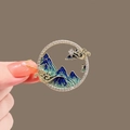 Macro view of a round enamel pendant featuring blue mountain landscapes and crystal inlay - Landscape Painting Style (X0303)