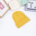 Flat lay of a bright yellow knitted beanie with a minimalist wooden frame and ceramic decor - M (56-58cm) / Yellow