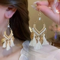 Dettaglio di orecchini boho dorati con nappe bianche e pendenti a foglia su una modella - Bianco (39# Gancio per l'orecchio)