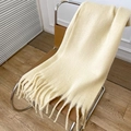 Soft beige faux cashmere scarf with fringe hanging on a leather chair in natural light - Beige