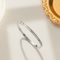 Minimalist silver steel bangle with white shell inlay and zircon accents on a gold tray - Silver