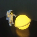 Floating astronaut figurine with glowing LED moon lamp and golden orbital ring detail - Planet Lamp + Astronaut