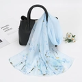 Light blue floral chiffon sun protection scarf draped over a black leather handbag - 150cm / Blue