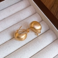 Minimalist matte gold C-shaped earrings displayed on a striped velvet jewelry case - 18K Gold Plated Brushed C-Shape (925 Sterling Silver Earring Post)