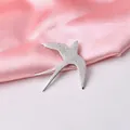 Dettaglio della spilla a rondine argento con piume incise su sfondo di raso rosa - Argento Opaco K