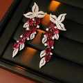Macro detail of silver floral tassel earrings with red oval gemstones in a black box - Silver Leaf Zirconia Red Gemstone Tassel Studs