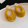 Detail of gold oval drop earrings with intricate woven texture on a white tray - Gold