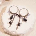 Dettaglio di orecchini a cerchio in argento con perline viola e nappe in metallo - Viola