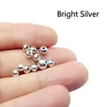 Primer plano de pequeñas cuentas plateadas en la punta de los dedos para joyería DIY - 3mm / Plata Brillante