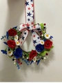 Detail of red and blue roses with white daisies and star ribbon on the festive wreath - Wreath Style B