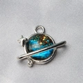 Macro shot of a planet charm with star nebula patterns on silver satin fabric - Style 11-Nebula Saturn