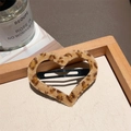 Close-up of a heart-shaped leopard print plush hair clip on a natural wooden tray - Leopard Heart Plush Clip